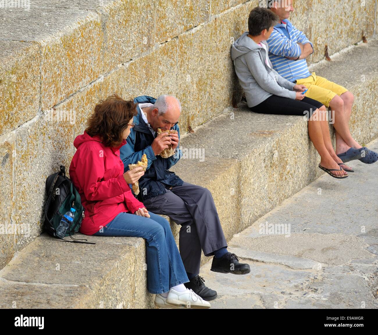 People eating and sitting on the sea wall in St ives Cornwall England uk Stock Photo
