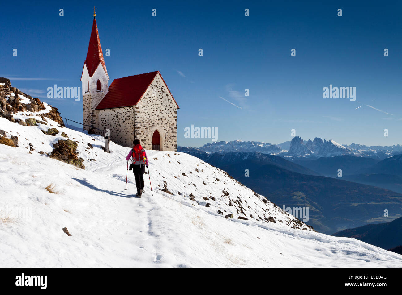 Hiker at the mountain church of Latzfonser Cross, infront of the Dolomites with Sasso Lungo, Sasso Piatto and Sellastock Stock Photo