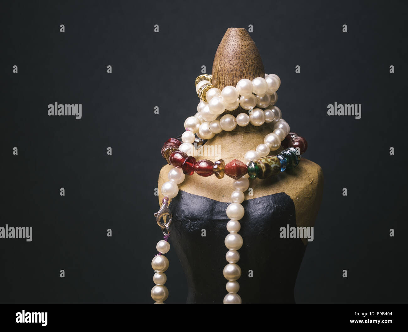 Miniature mannequin with necklaces isolated on dark background Stock Photo