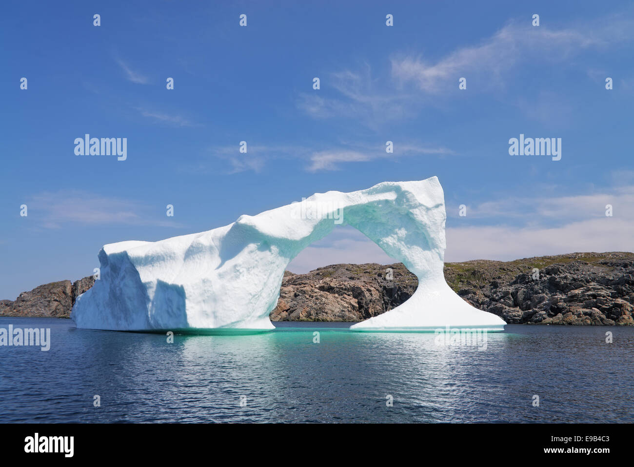 Iceberg in front of a rocky island near Twillinggate, Newfoundland and Labrador, Canada Stock Photo