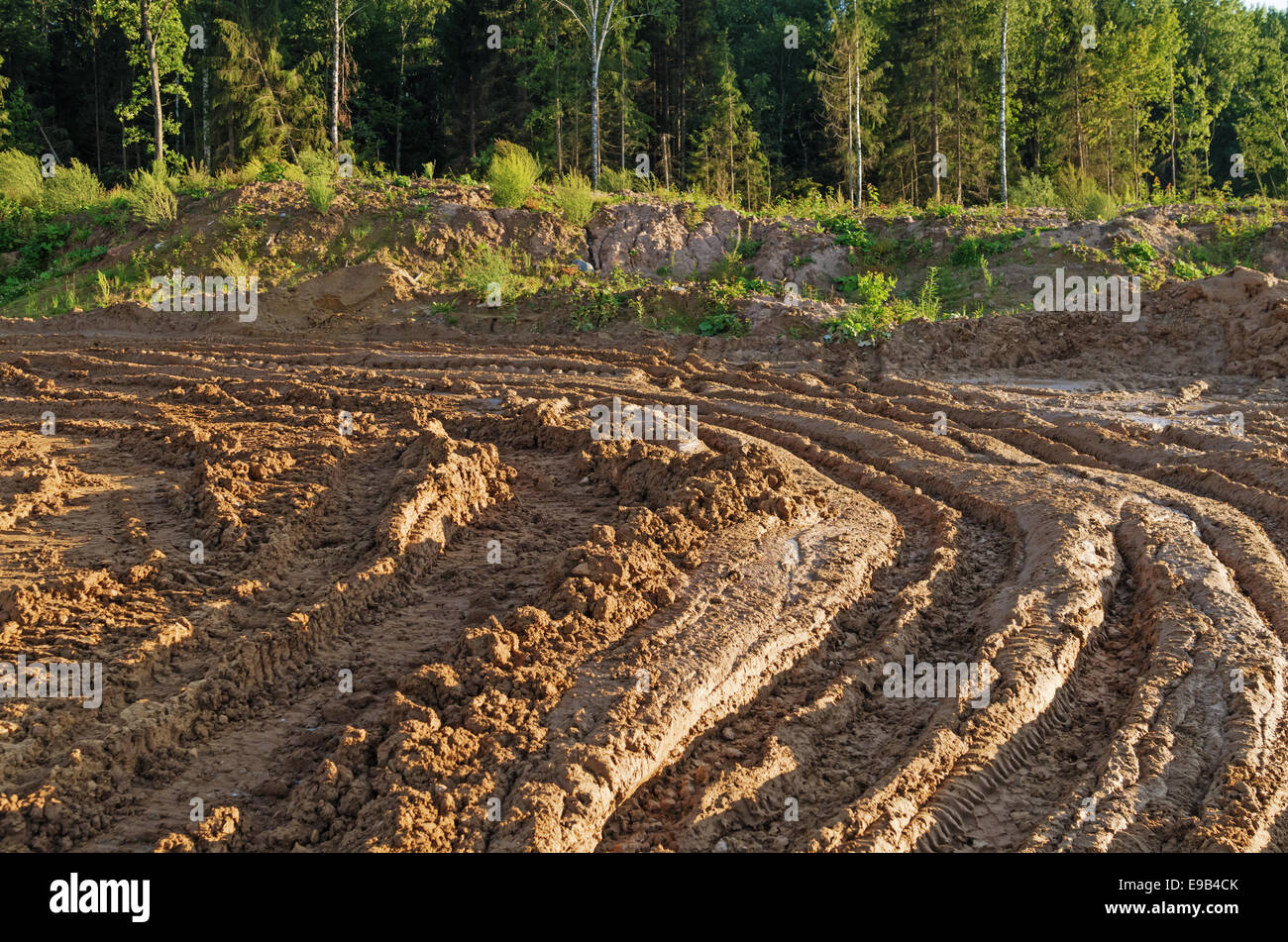 Construction of Vitebsk hydroelectric power station. The dirty clay road and the wood near building. Stock Photo