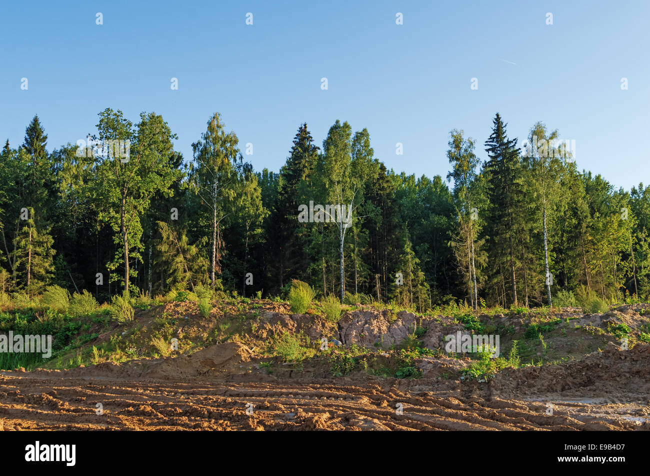 Construction of Vitebsk hydroelectric power station. The dirty clay road and the wood near building. Stock Photo