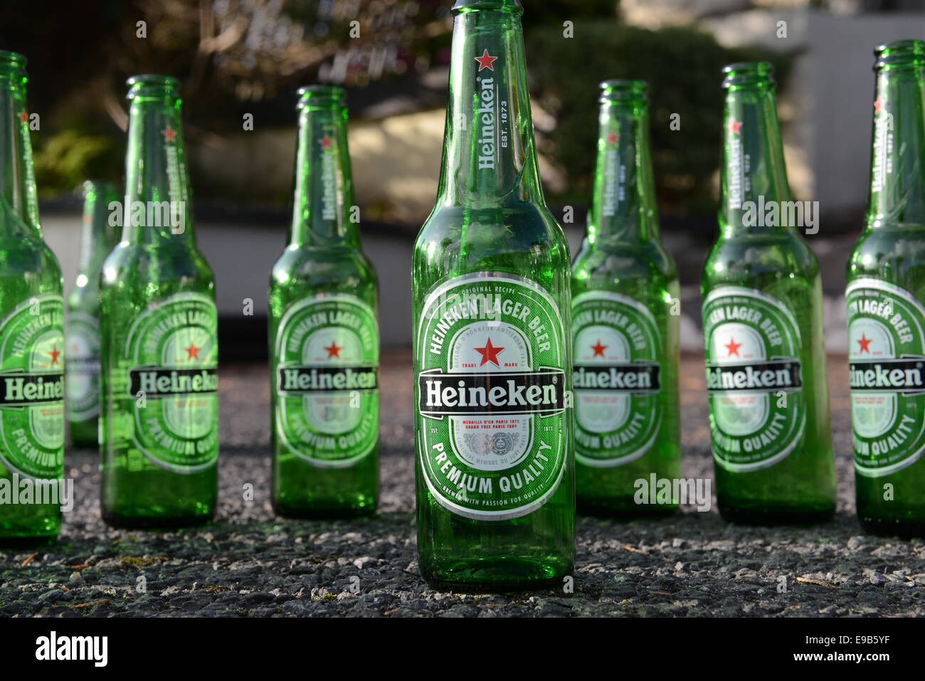 A row of Heineken Bottles with one at the front on concrete Stock Photo