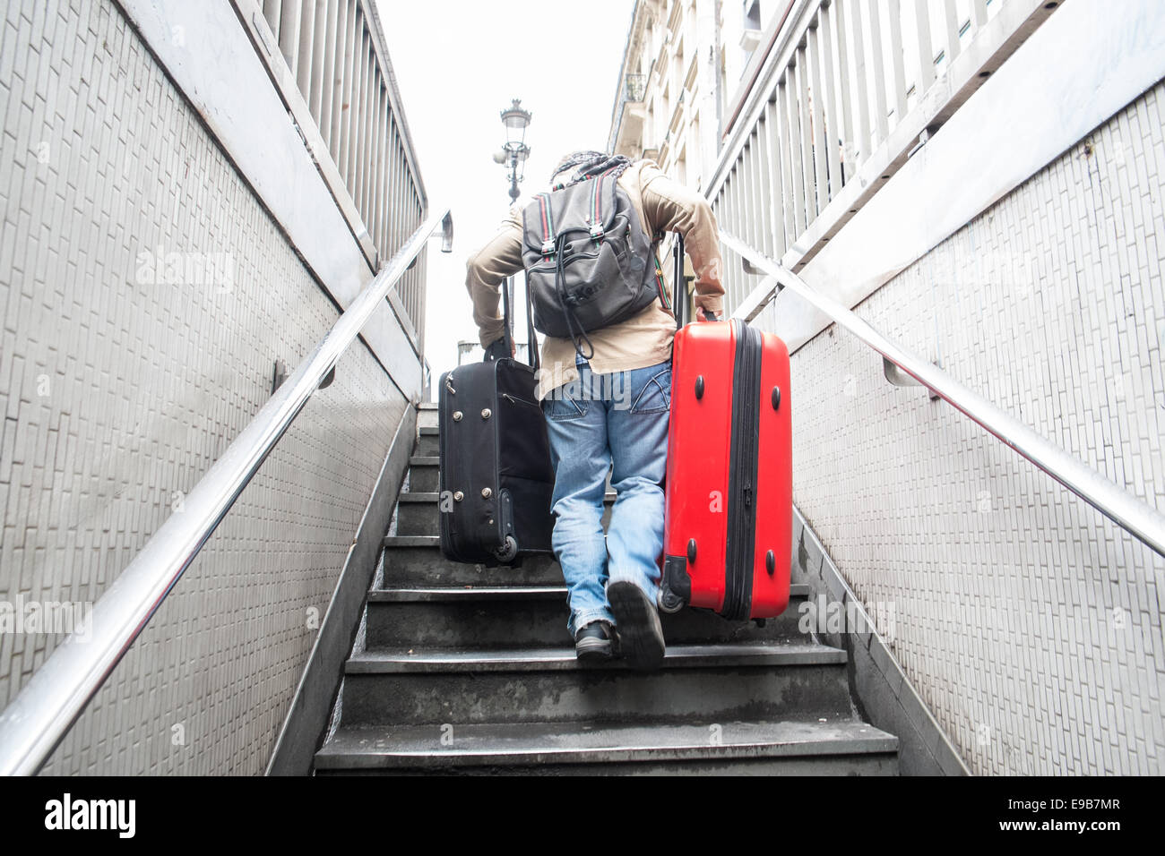 Male,Man,Guy,struggling,with,bags,and,while,exiting Metro Station while carrying heavy bags/suitcases,luggage,up a flight of stairs in Paris, France. Stock Photo
