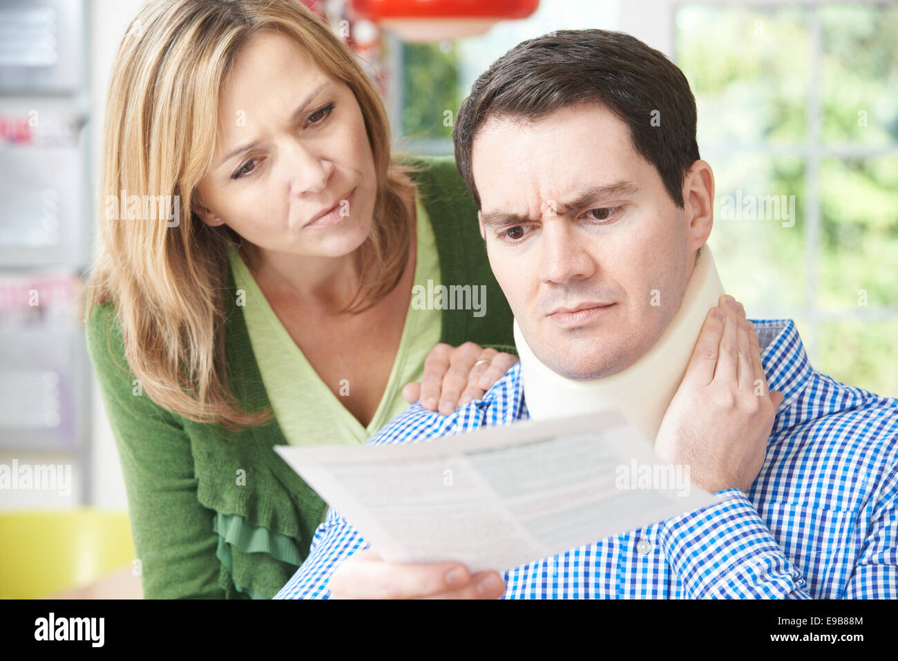 Couple Reading Letter In Respect Of Husband's Neck Injury Stock Photo