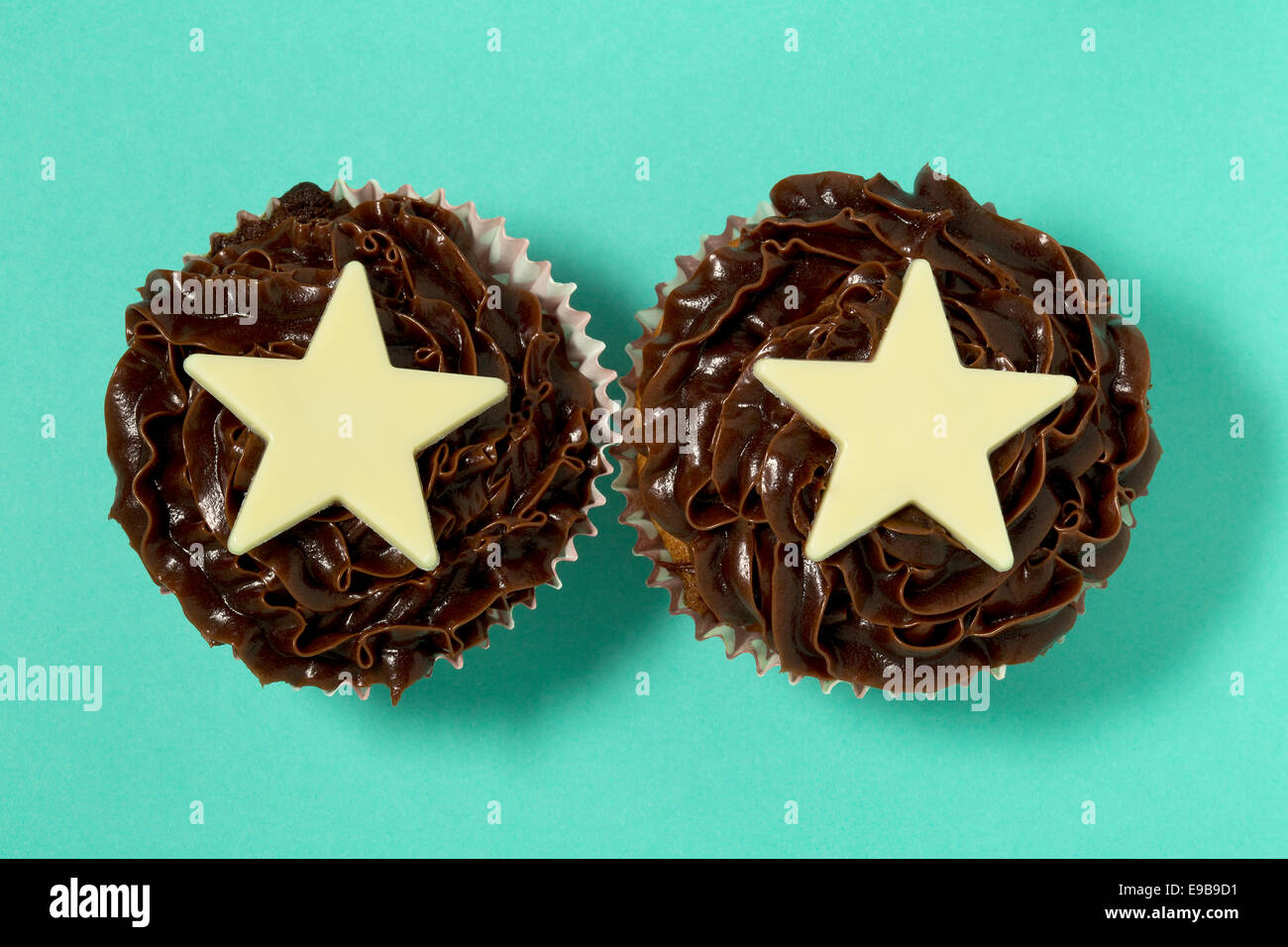 Two chocolate cupcakes with white chocolate stars on a turquoise background Stock Photo