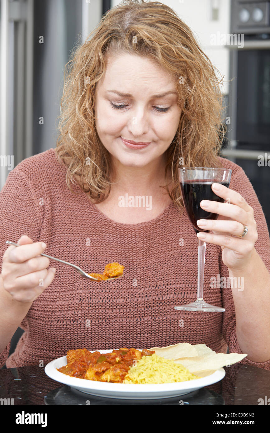 Guilty Woman Eating Takeaway Curry And Drinking Wine Stock Photo