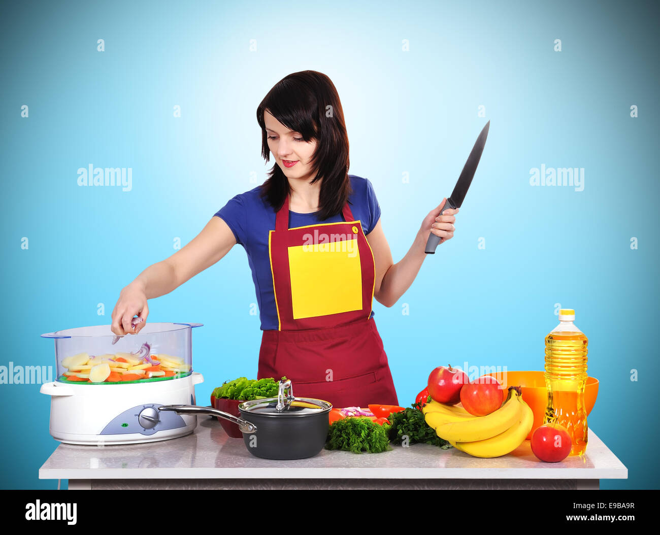 young housewife with knife standing in kitchen Stock Photo