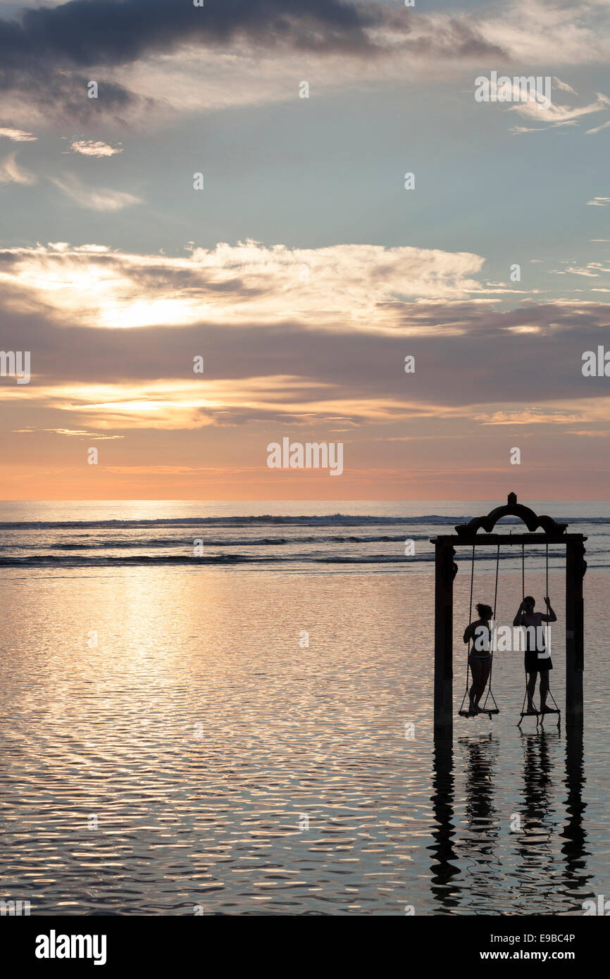 Silhouette of two people on sea swing at sunset, 'Gili Trawangan', 'Gili Islands', Indonesia Stock Photo