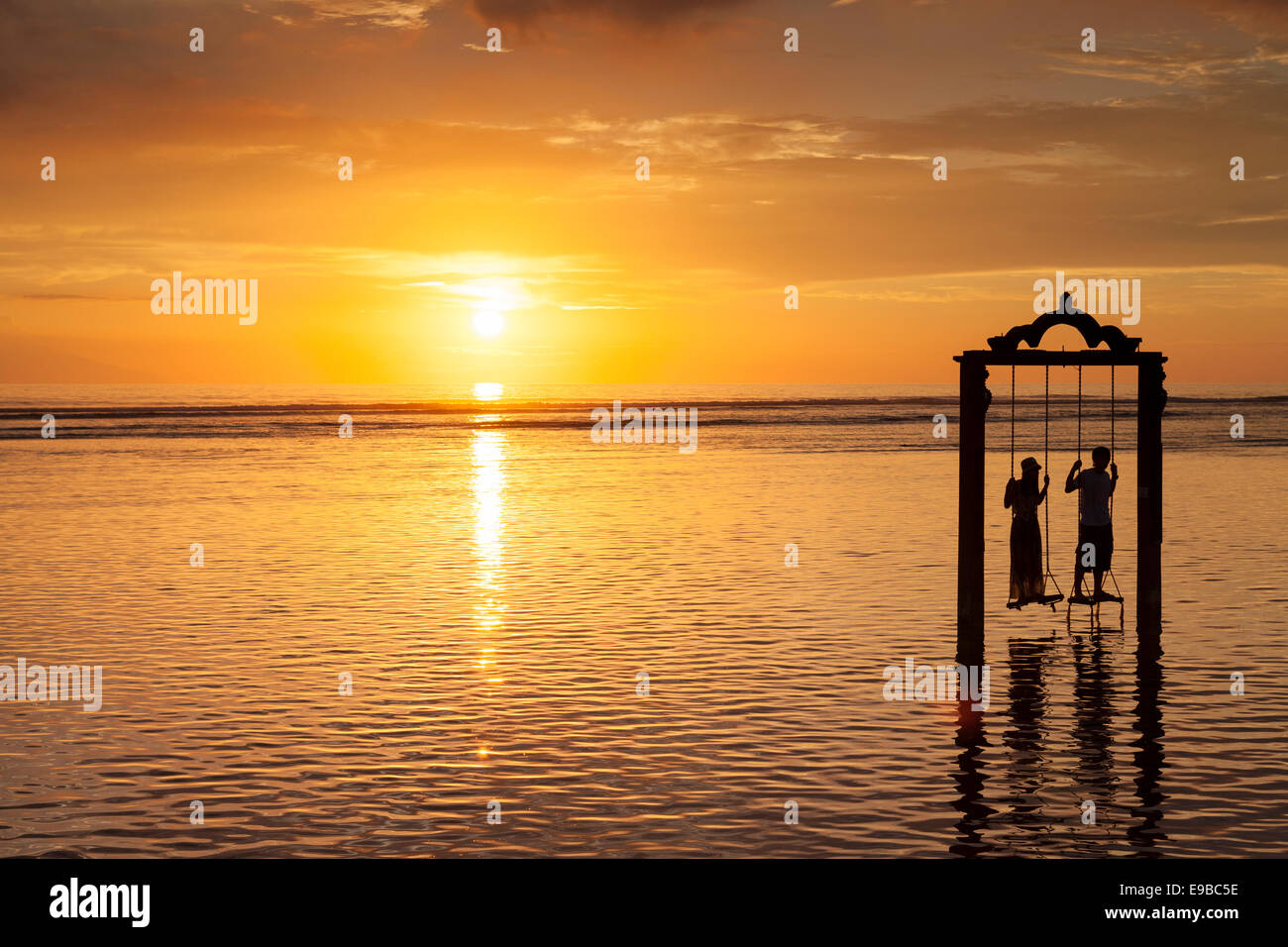 Man and woman on sea swing at sunset, 'Gili Trawangan', 'Gili Islands', Indonesia Stock Photo