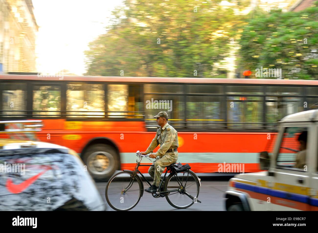 A man in military uniform rides his bicycle in the busy Mumbai traffic Stock Photo