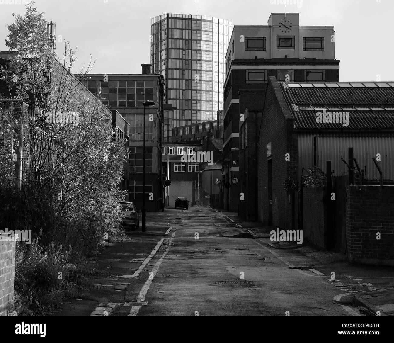 Old factories on a Sheffield back street, looking towards a modern office block in the distance Stock Photo