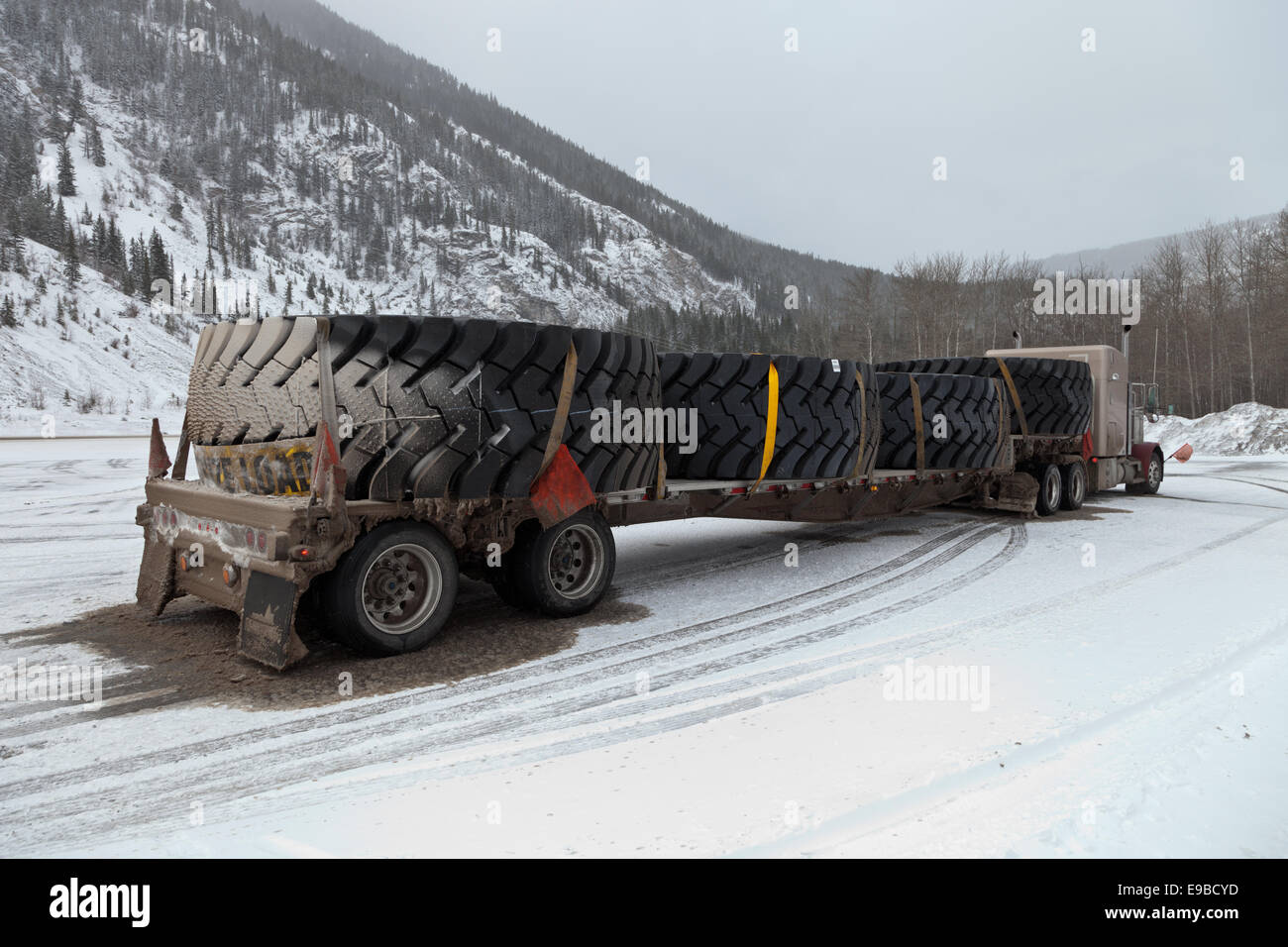 peterbilt 379 Semi trailer with a flatdeck oversize load of huge giant large mining tyres with warning flags snow and ice covered in pullout winter Stock Photo