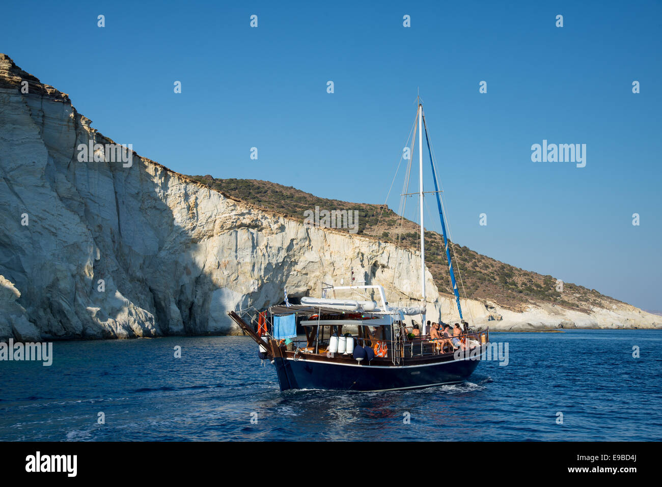 boat alongside the white cliffs of gerontas at milos in greece Stock Photo