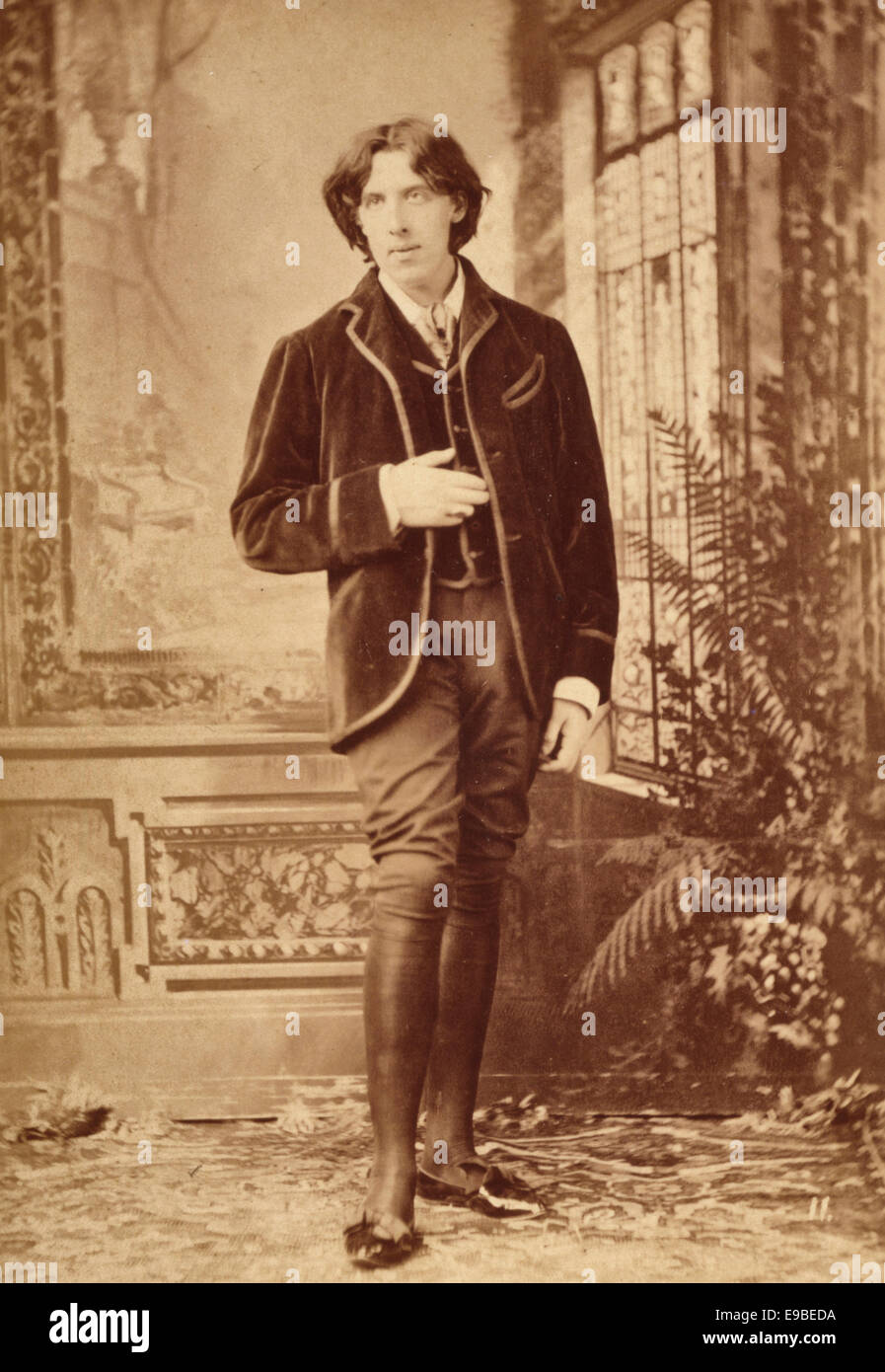 Summary: Oscar Wilde, full-length portrait, standing with right hand at waist, facing front with head turned to the left, window behind left shoulder, circa 1882 Stock Photo