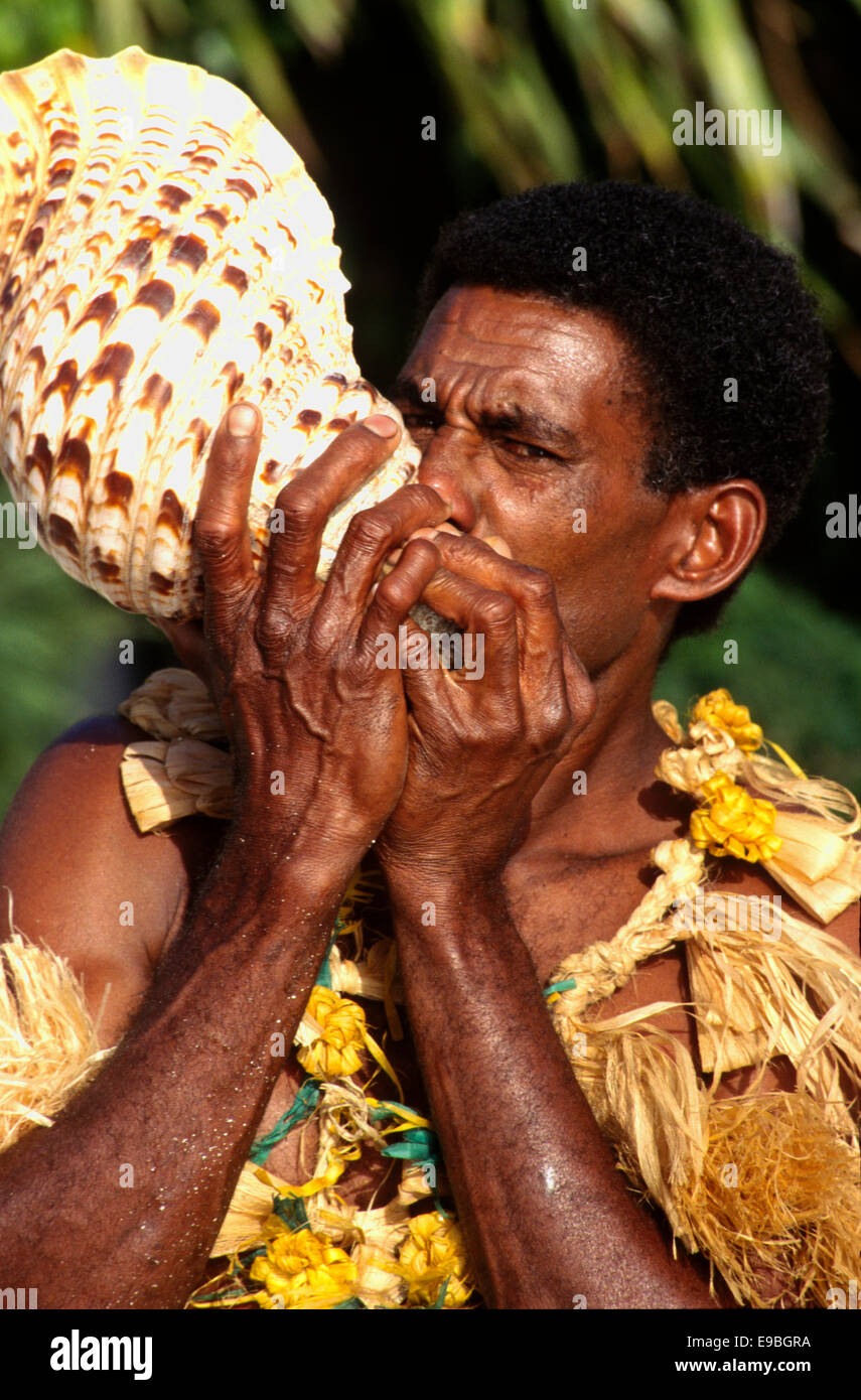 Fijian performs on the 'Davui' (conch shell) at Turtle Island, Fiji Stock Photo