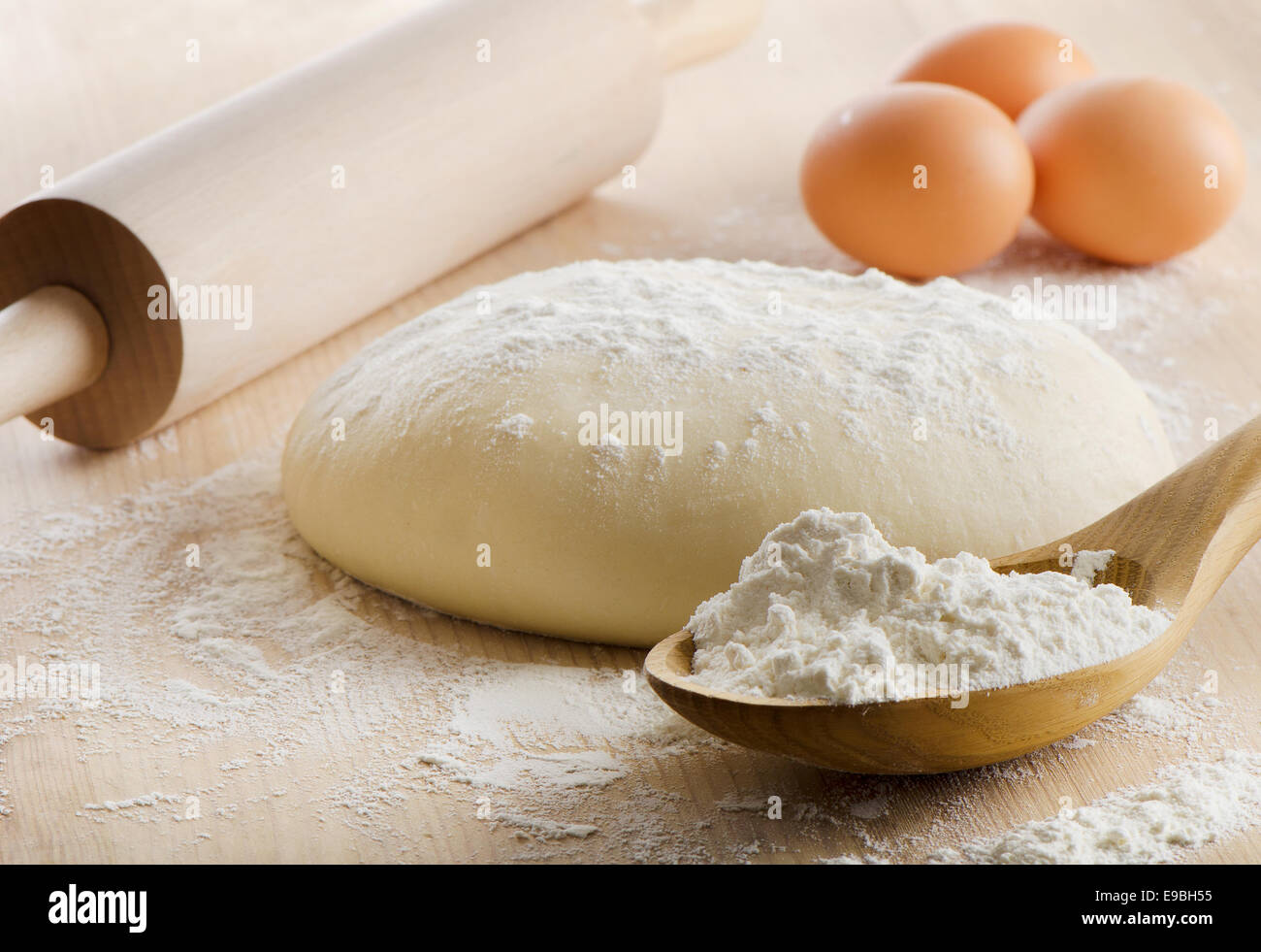 Dough with rolling pin on wooden table. Selective focus Stock Photo