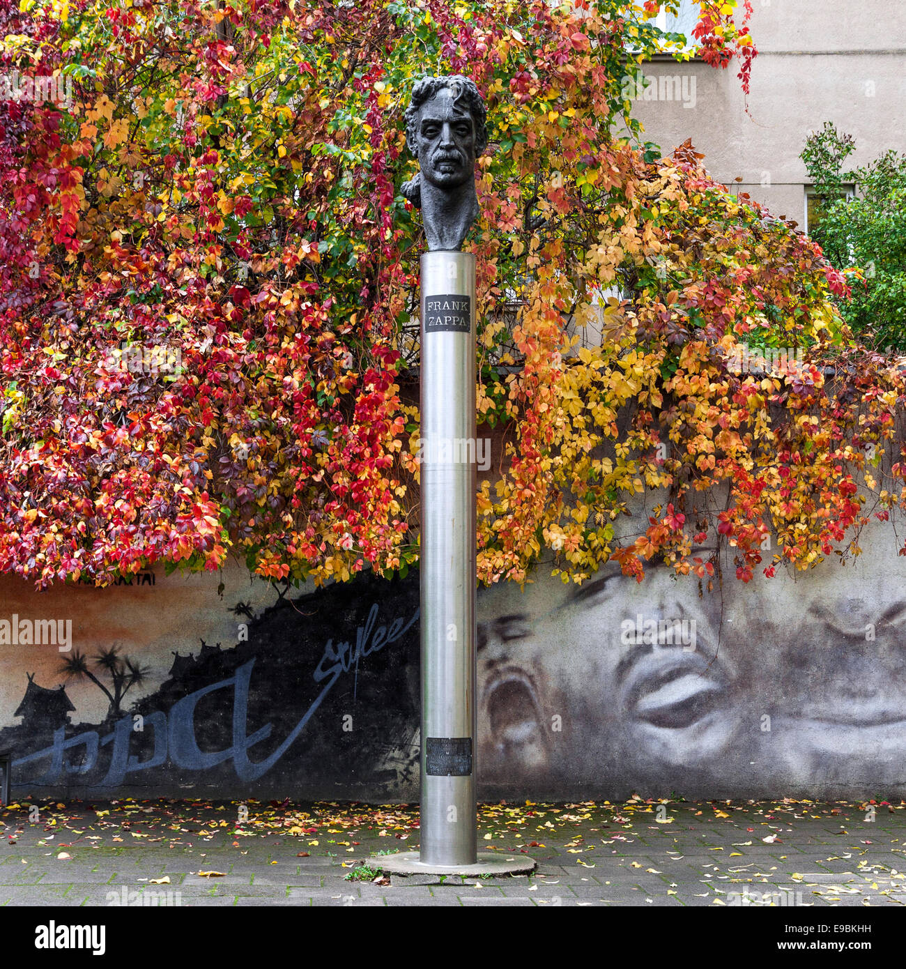 Monument dedicated to Frank Zappa in Vilnius, Lithuania. Monument is placed against graffiti wall with autumn foliage Stock Photo