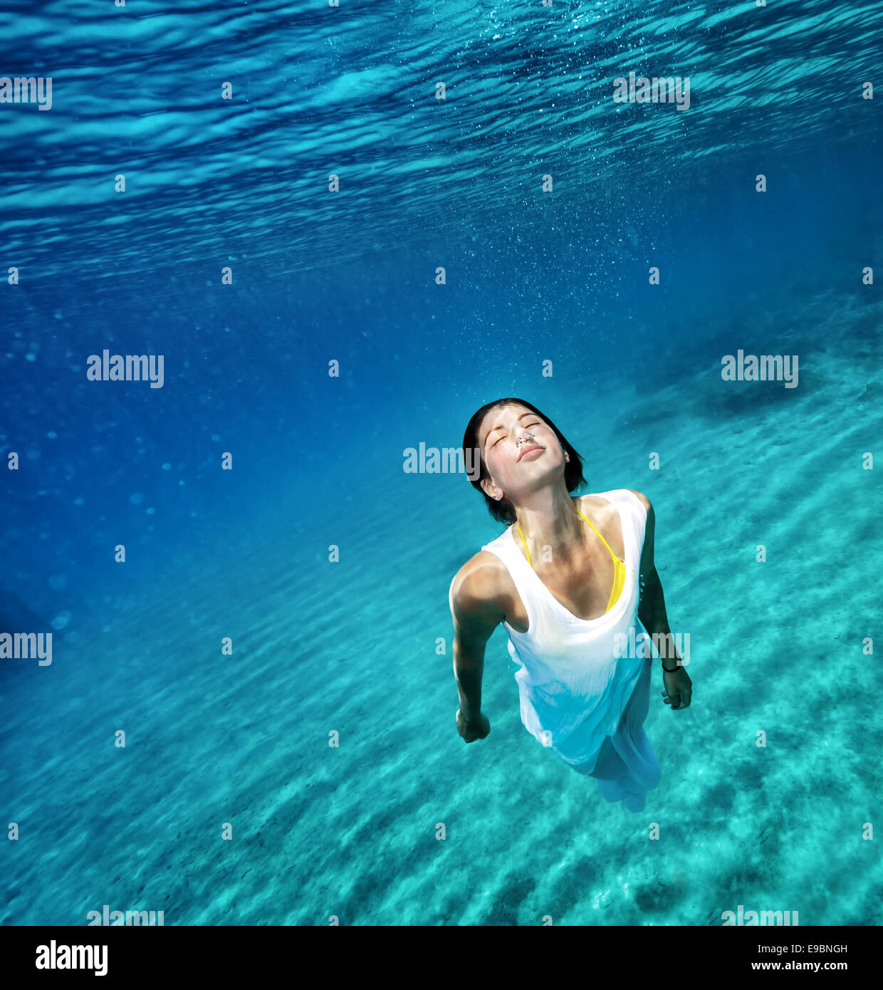 Beautiful female wearing white dress underwater, active lifestyle