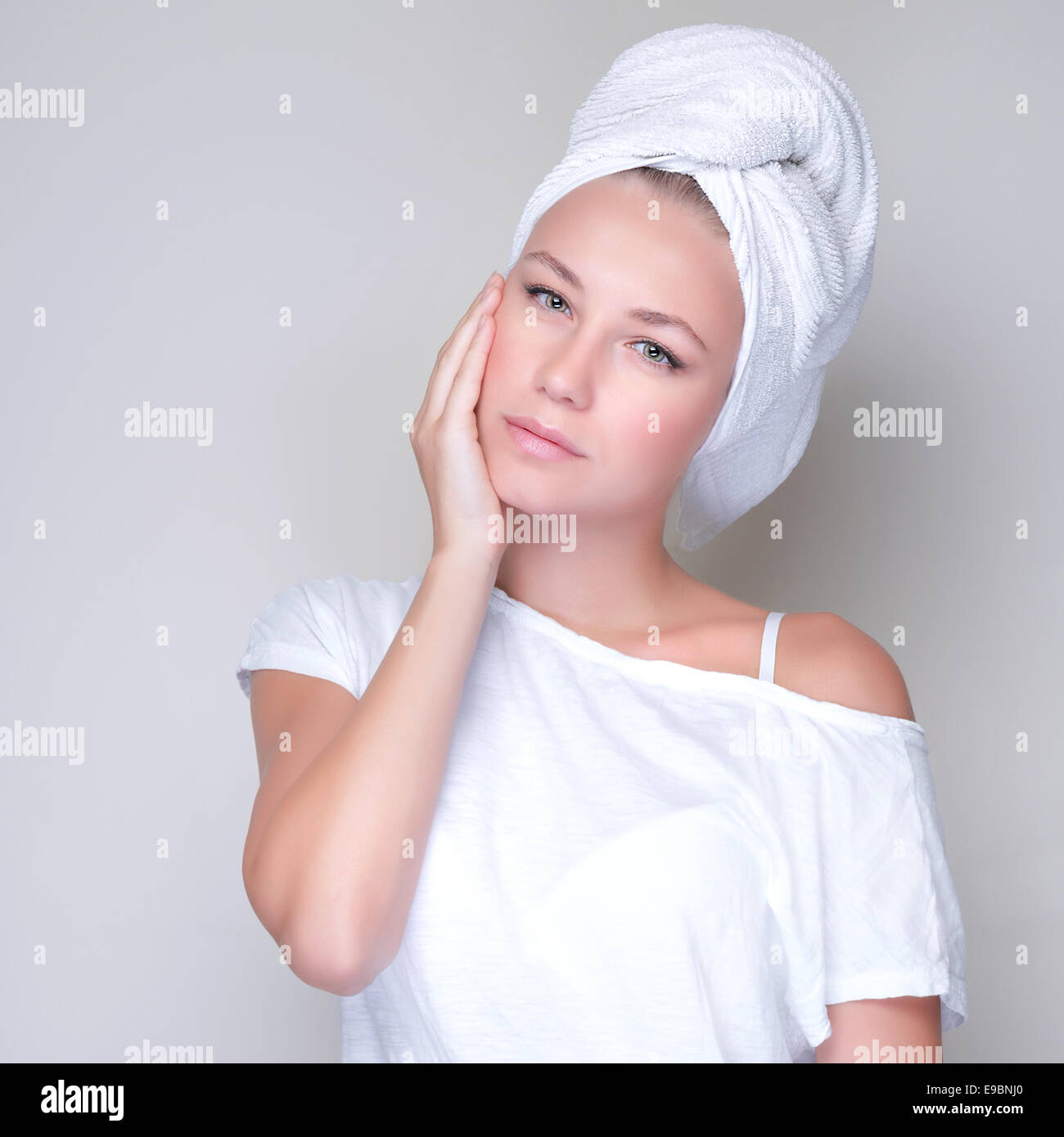 Closeup portrait of beautiful young woman with towel on head isolated on gray background, enjoying day spa, beauty treatment Stock Photo