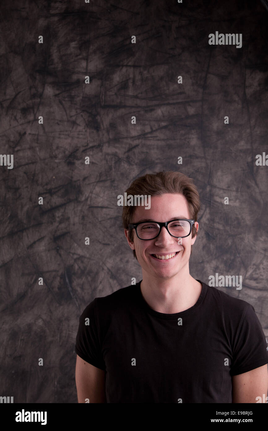 nerdy guy smiling at us in front of a blackboard Stock Photo