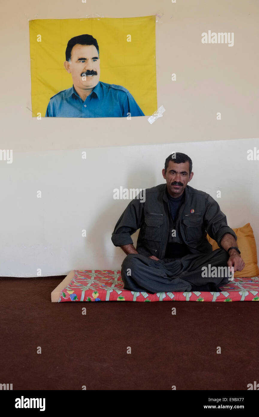 A Kurdish fighter of the People's Defense Forces HPG the military wing of the Kurdistan Workers' Party PKK sits with figure of former PKK militant leader Abdullah Ocalan in a HPG compound in northern Iraq Stock Photo