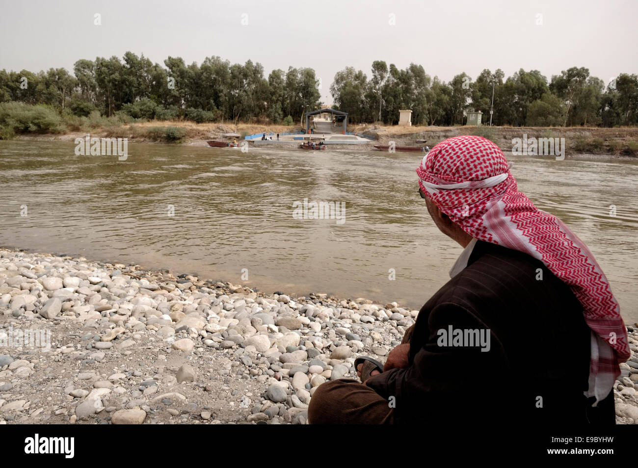 A Kurdish man looking across the Tigris river at the Faysh Khabur or Fishkhabur - Simalka border crossing from Syria’s northeastern Kurdish area into Iraq’s Kurdistan region. Stock Photo