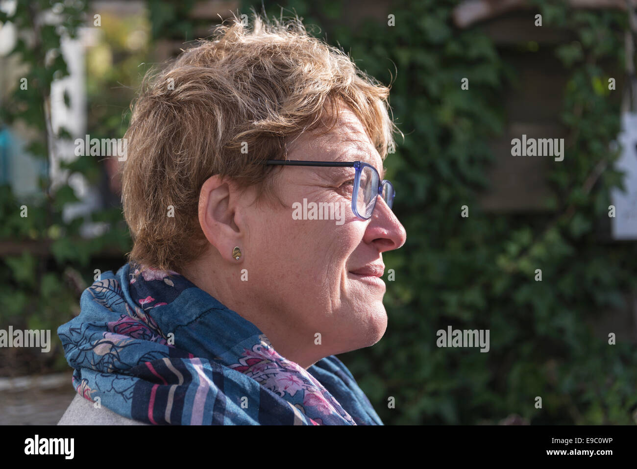 woman with golden hair and glasses thinking in the garden Stock Photo