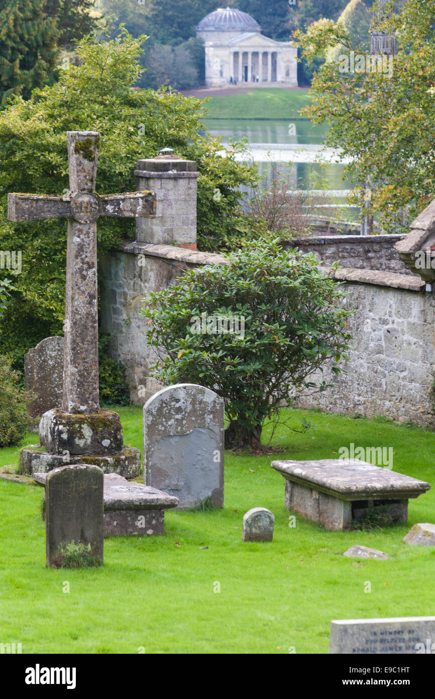 cemetery at church of St Peter's at Stourton, with Pantheon in Stourhead Gardens in the distance, Wiltshire in October Stock Photo