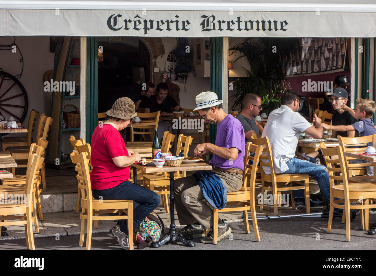 Tourists with hats eating Breton galettes at Crêperie Bretonne in France Stock Photo