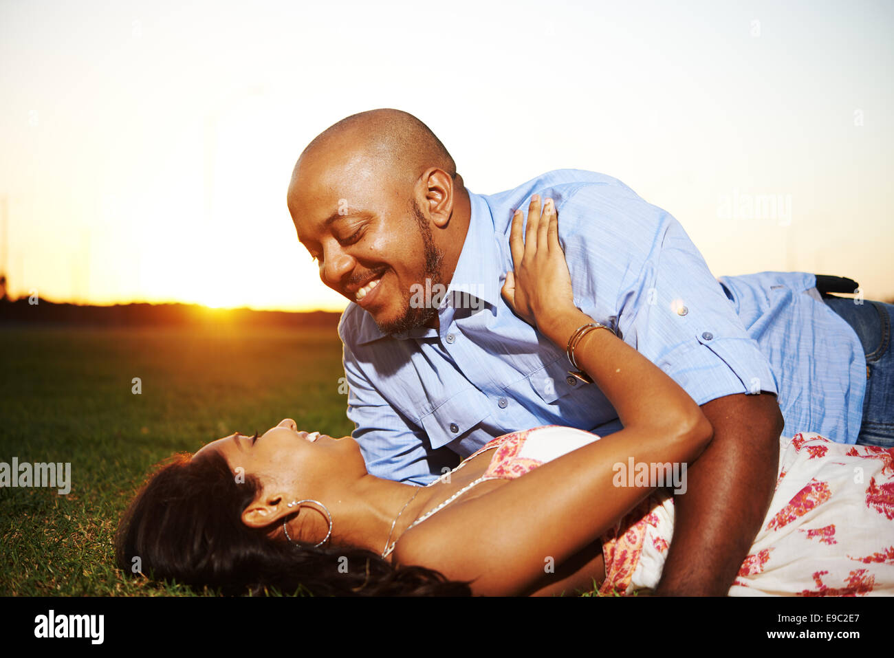 Coupling laying in grass during sunset laughing Stock Photo