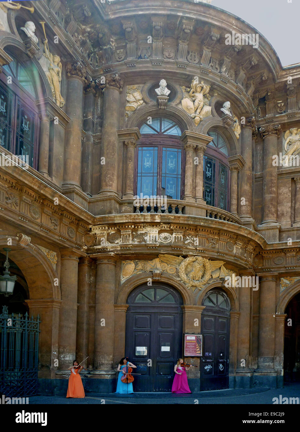 The Bellini Theatre, built in 1890 is considered one of the most beautiful opera houses in Italy, and is located on the Piazza Bellini. Before that pours a picturesque fountain from snake heads be water in a large bowl. A group of female musicians are sere Stock Photo