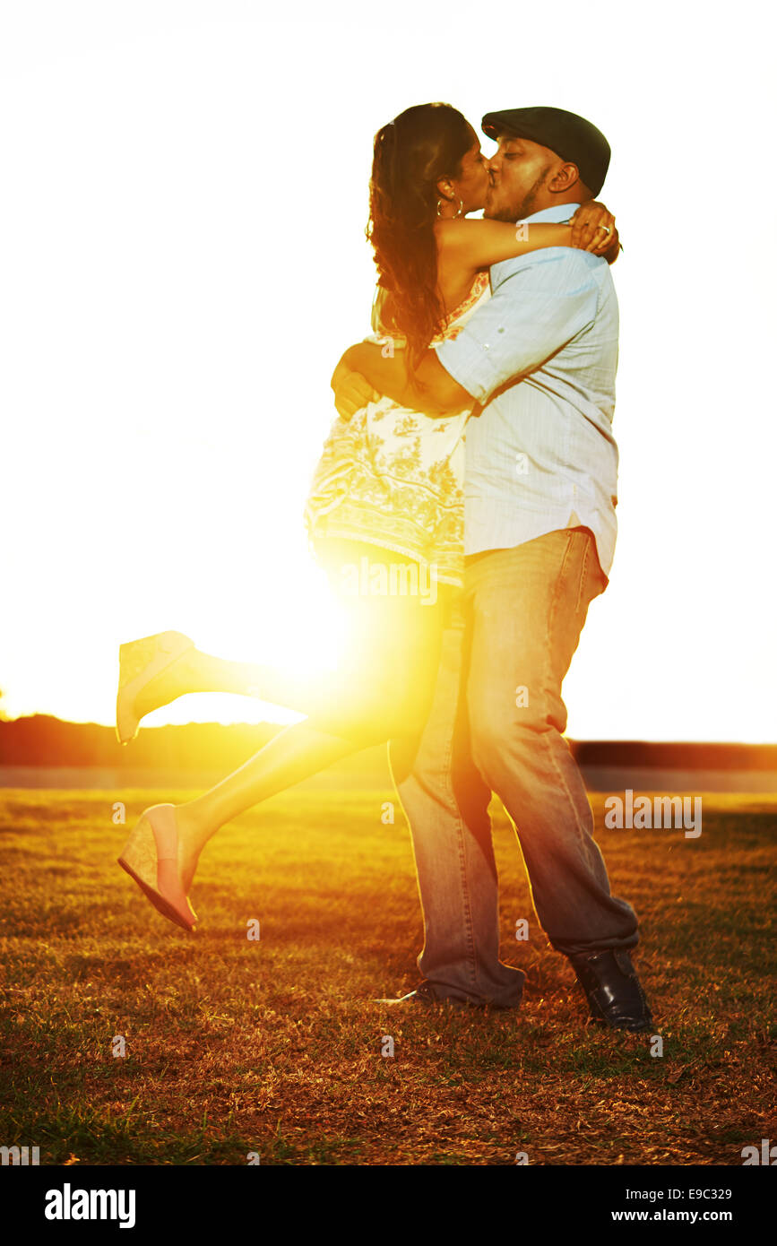 Couple twirling and kissing during sunset at a park Stock Photo
