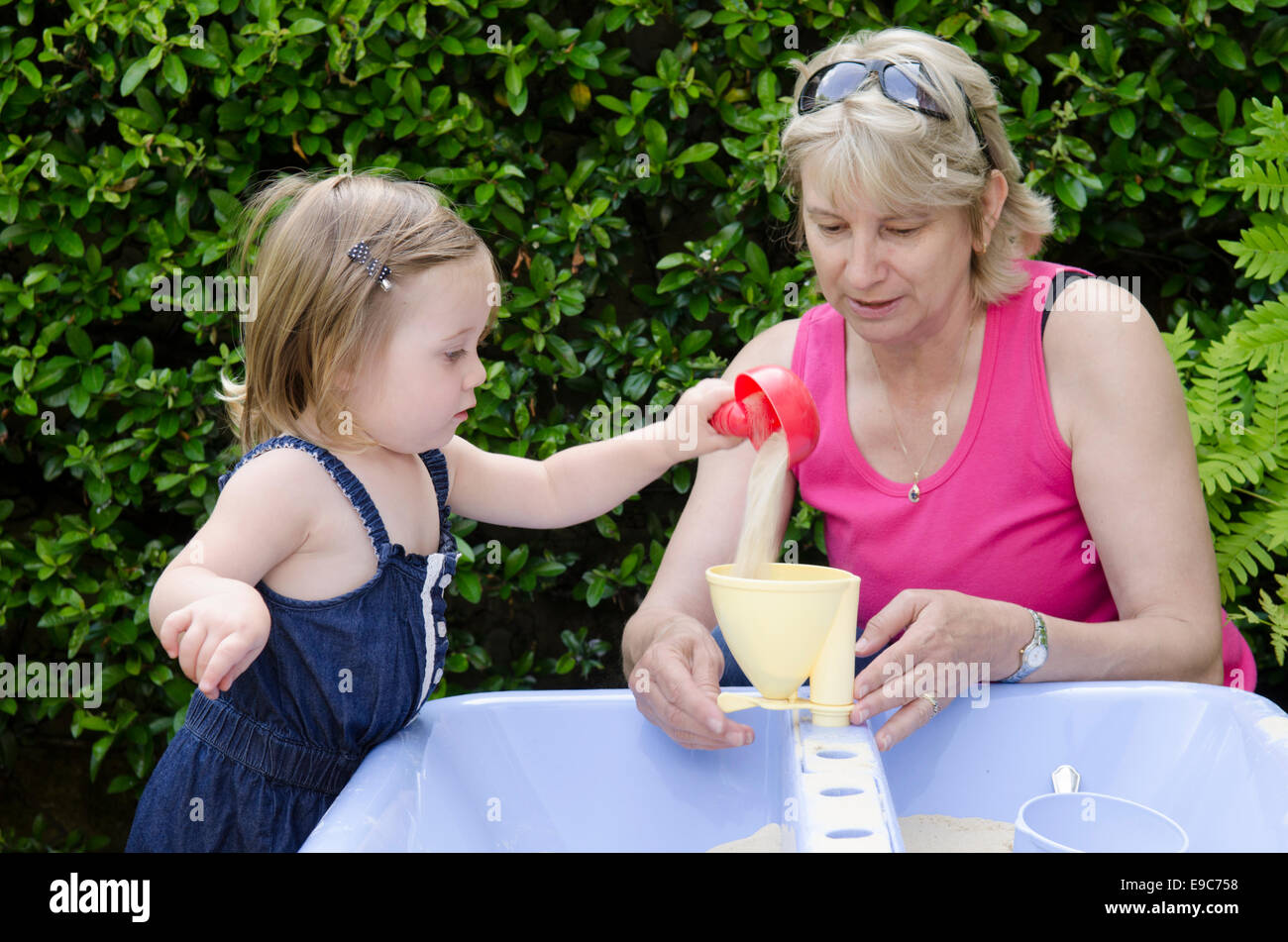 Grandmother playing in sandpit with granddaughter. UK Stock Photo