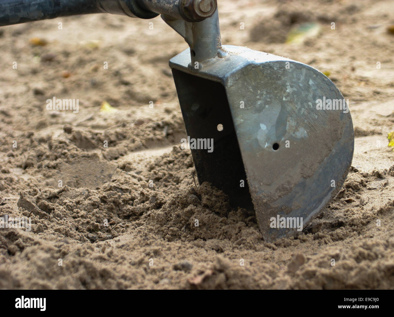 Child's sit on sand digger bucket digging in sand Stock Photo