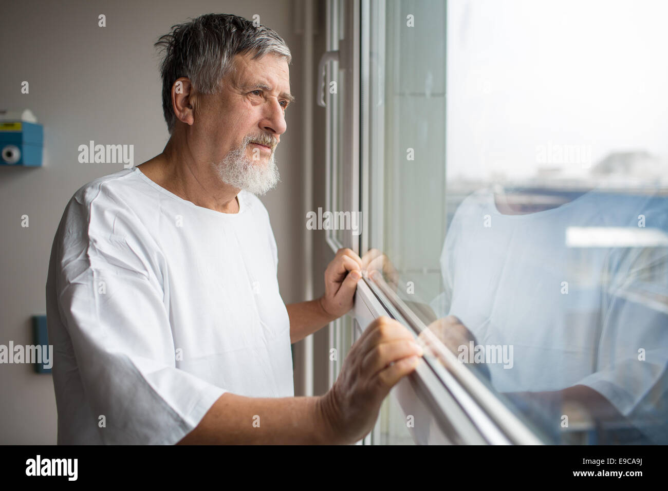 Patient at a hospital, looking from a window in his room, doing much better after the surgery Stock Photo