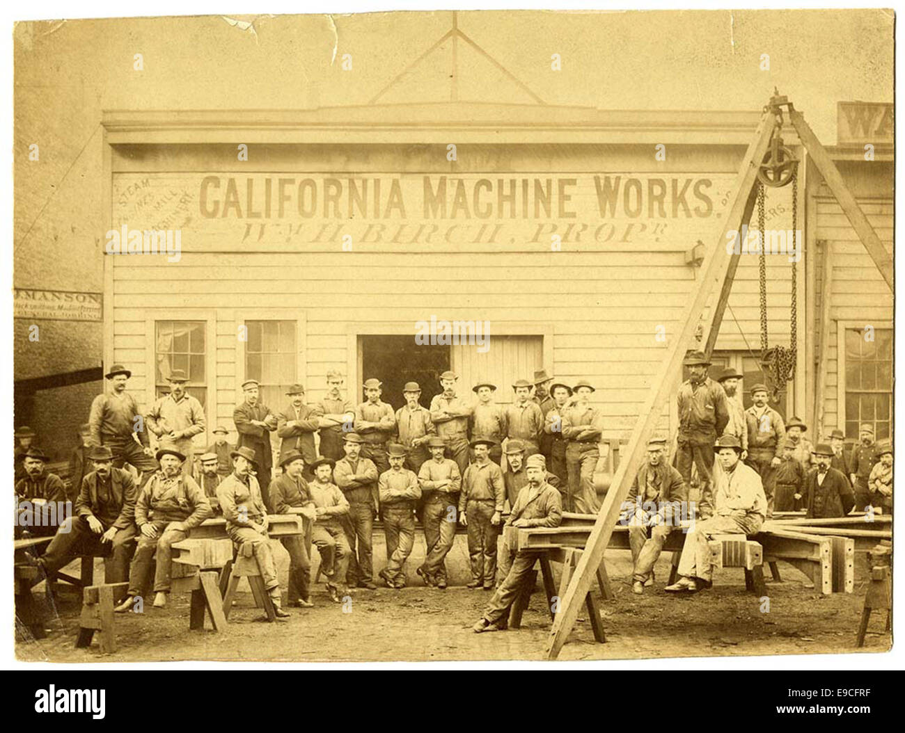 Photograph of employees at the California Machine Works in San Francisco around 1880. The workers are posing in their work clothes in front of the industrial building, offering a glimpse into the manufacturing industry during the late 19th century. Stock Photo