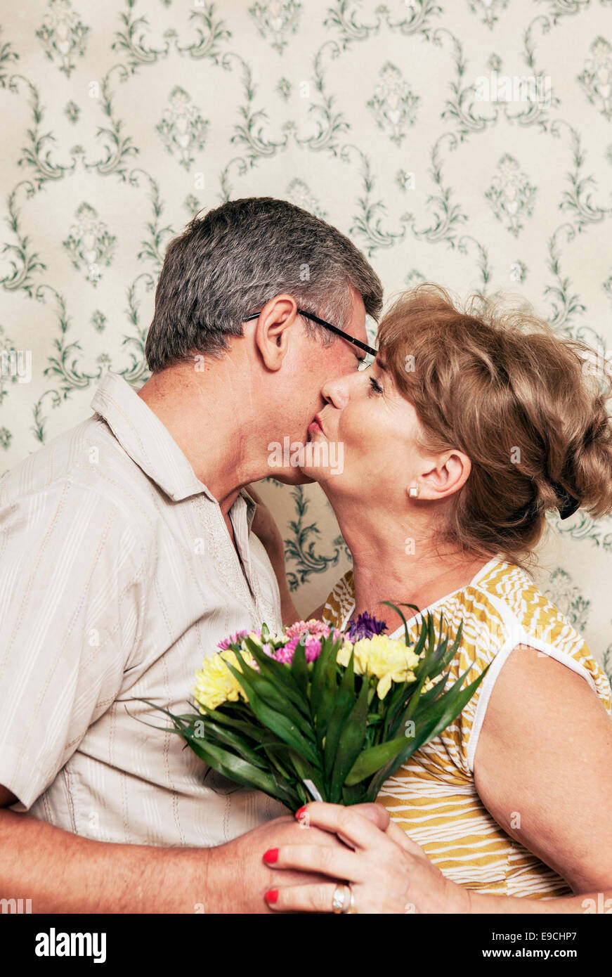 Adult couple kissing each other and holding bouquet of flowers Stock Photo