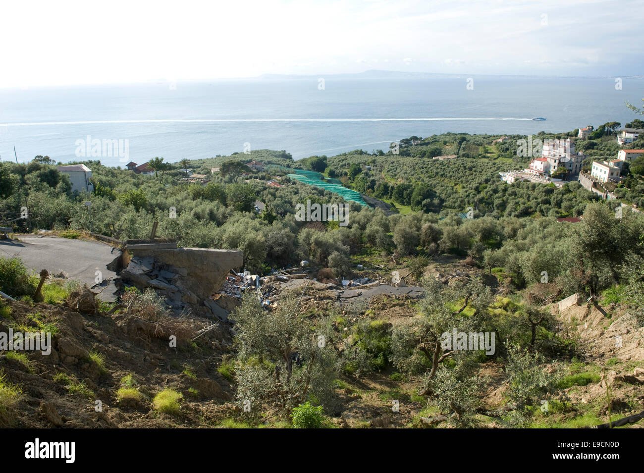 A flood damaged coastal road through olive groves and farmland, which has collapsed after heavy rain on the Bay of Naples near S Stock Photo