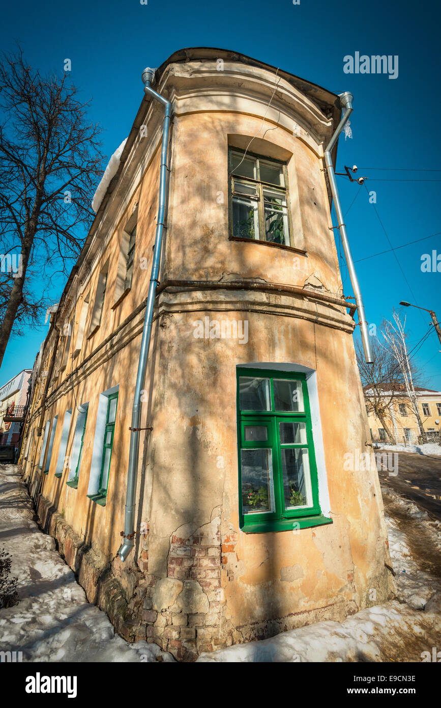 Old building exterior view, requiring repair. Dirty-orange color building. Multiple windows with green frames. Stock Photo