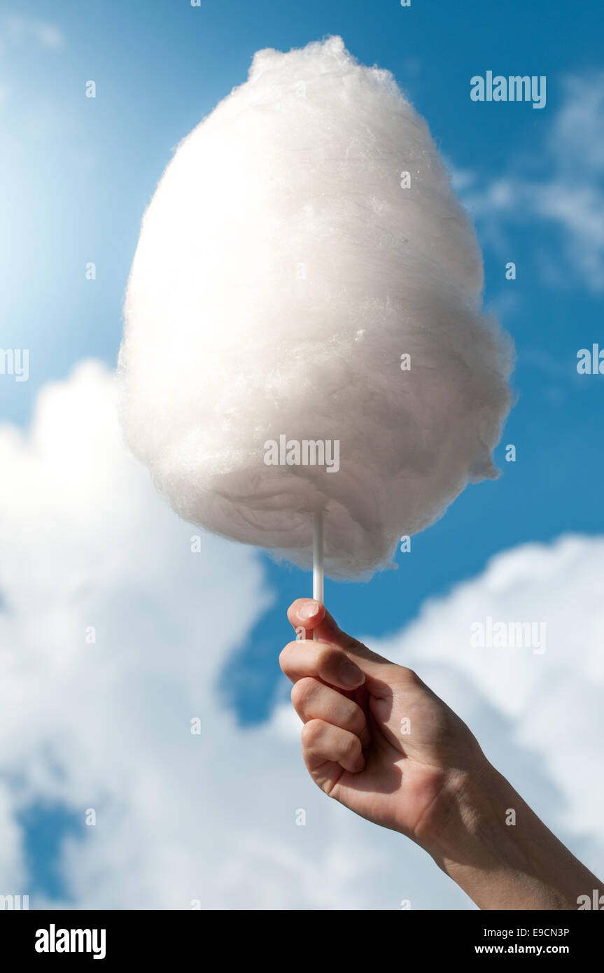 Holding Sweet Cotton Candy on Stick Isolated on Blue White Sky Background. Stock Photo