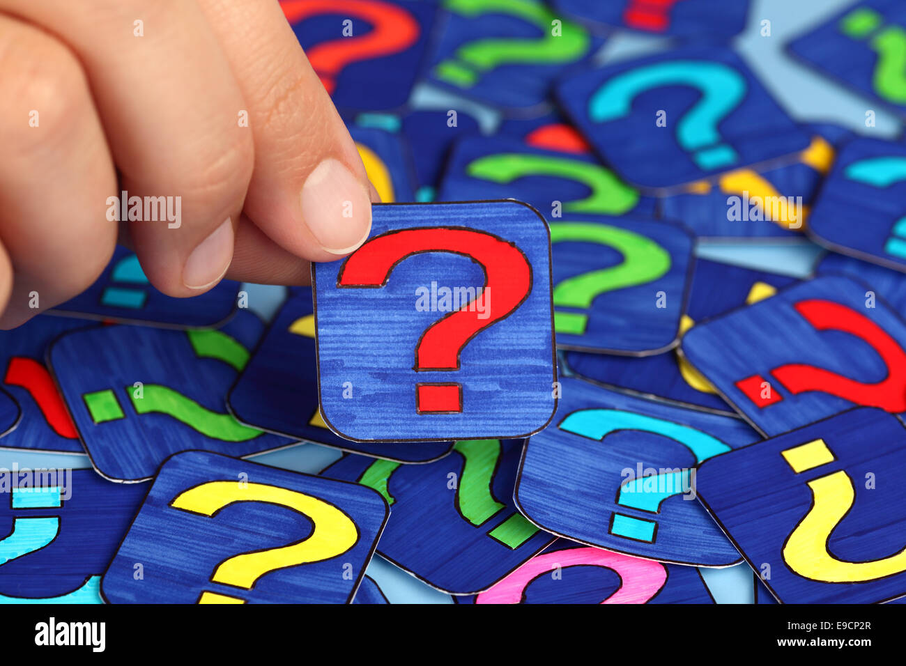 Woman's hand hold red question mark with background of question marks. Question Marks drawn by