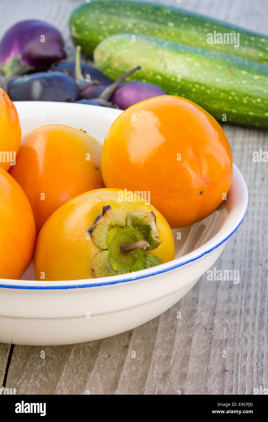 bowl with sharon fruits, courgettes, eggplant Stock Photo