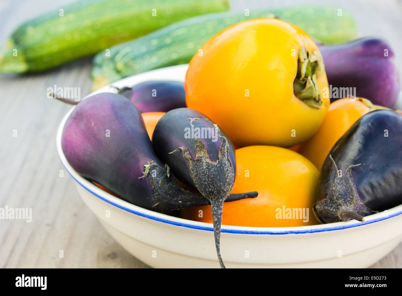 bowl with sharon fruits, courgettes, eggplant Stock Photo