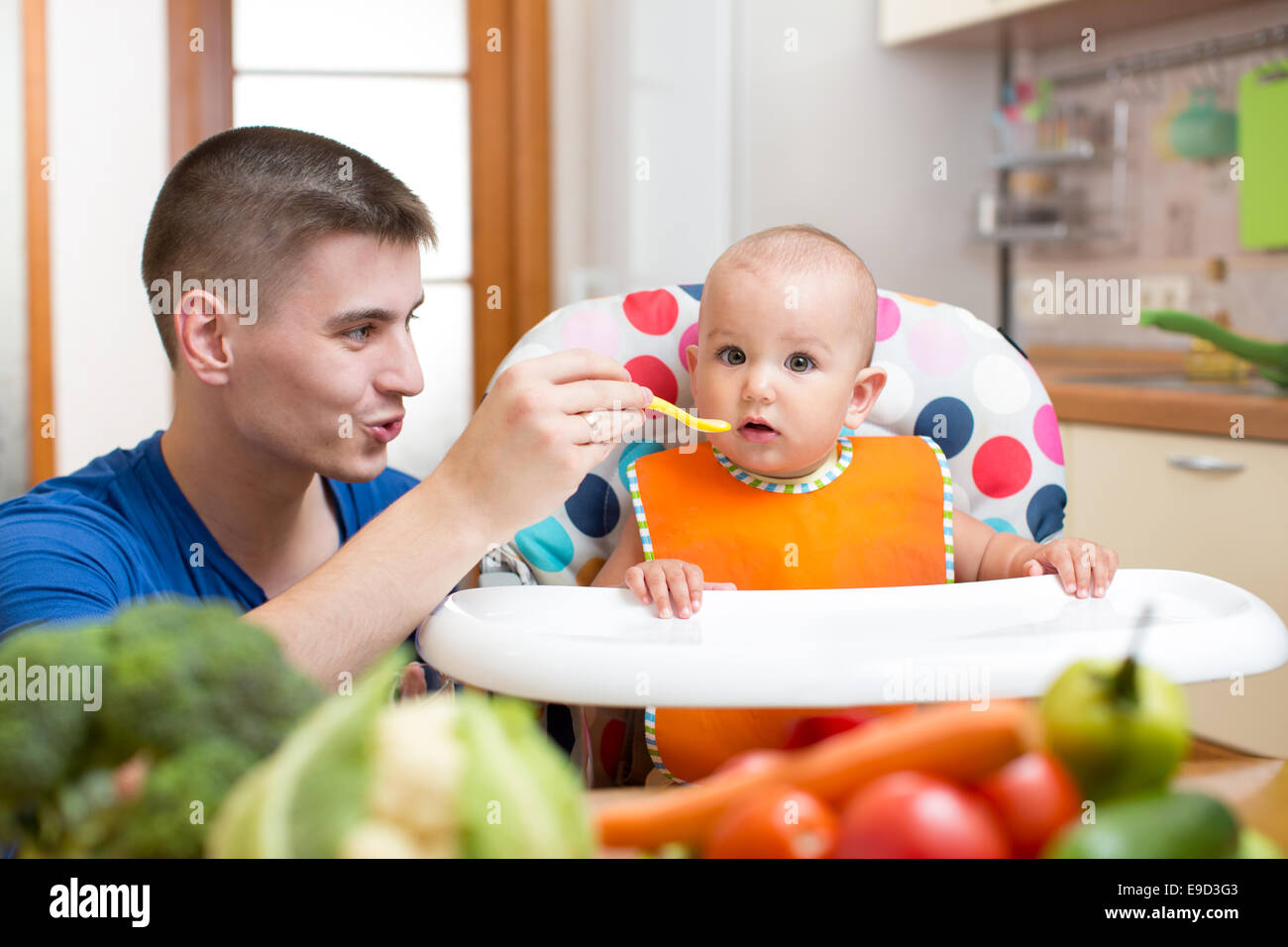 young dad feeding his baby at kitchen Stock Photo