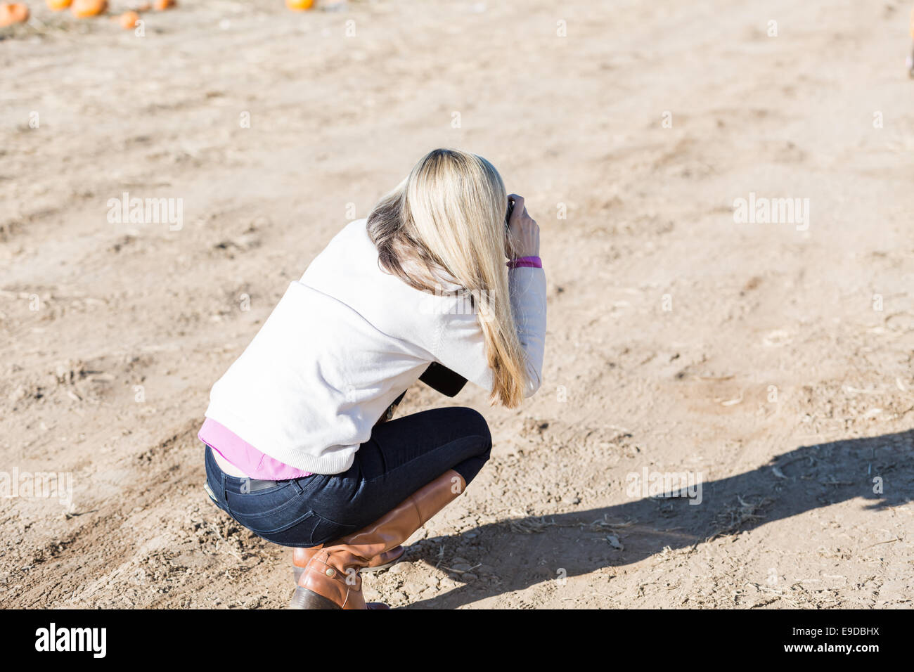 Young mother taking pictures of her kids at the pumpkin patch. Stock Photo