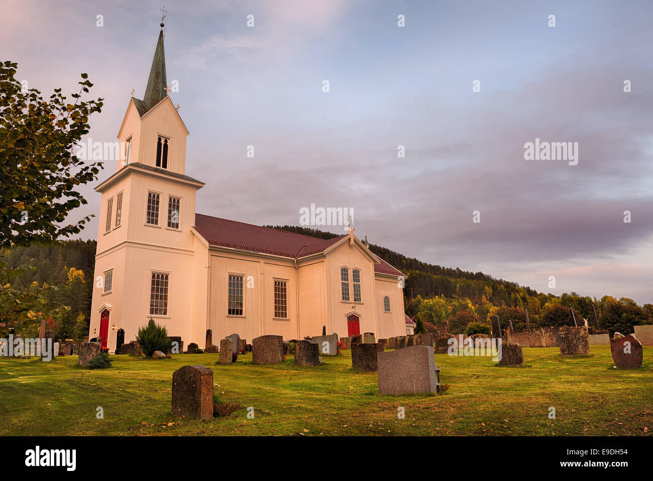 A white stave church in a Norway  village at sunset. Hdr image. Stock Photo