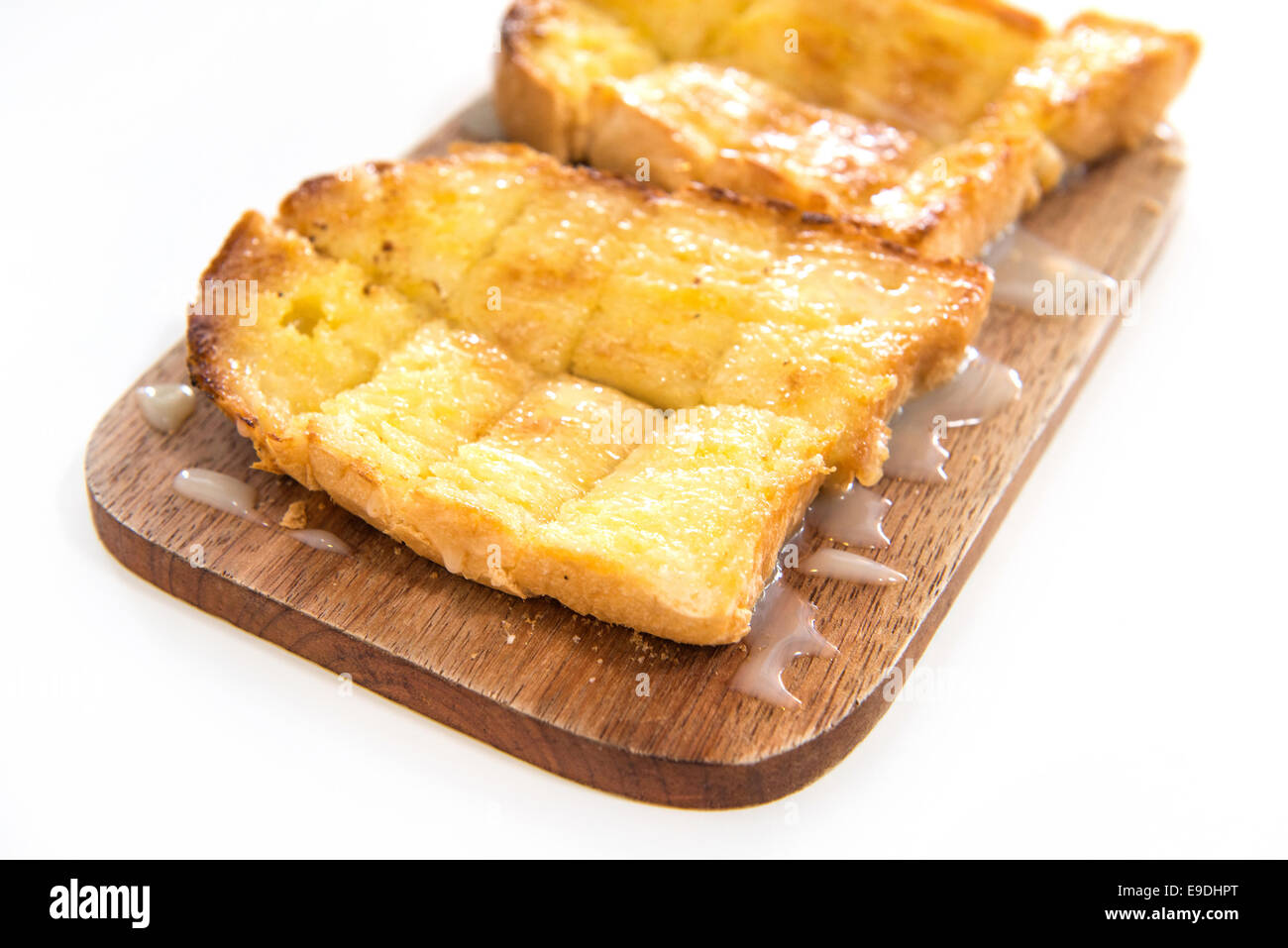 Bread toast and condensed milk on wooden plate over white background