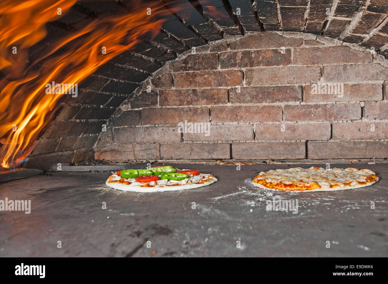 Two pizzas cooking in an open oven with gas flame Stock Photo Alamy