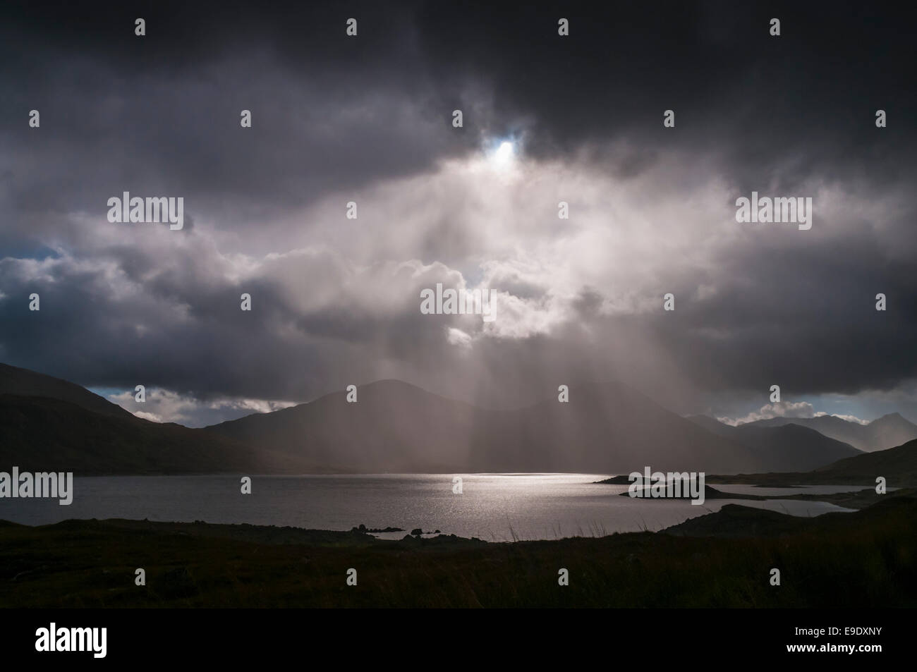 Looking Towards Sgurr Mor and Sgurr an Fhuarain across Loch Quoich through the rain and crepuscular rays. Stock Photo